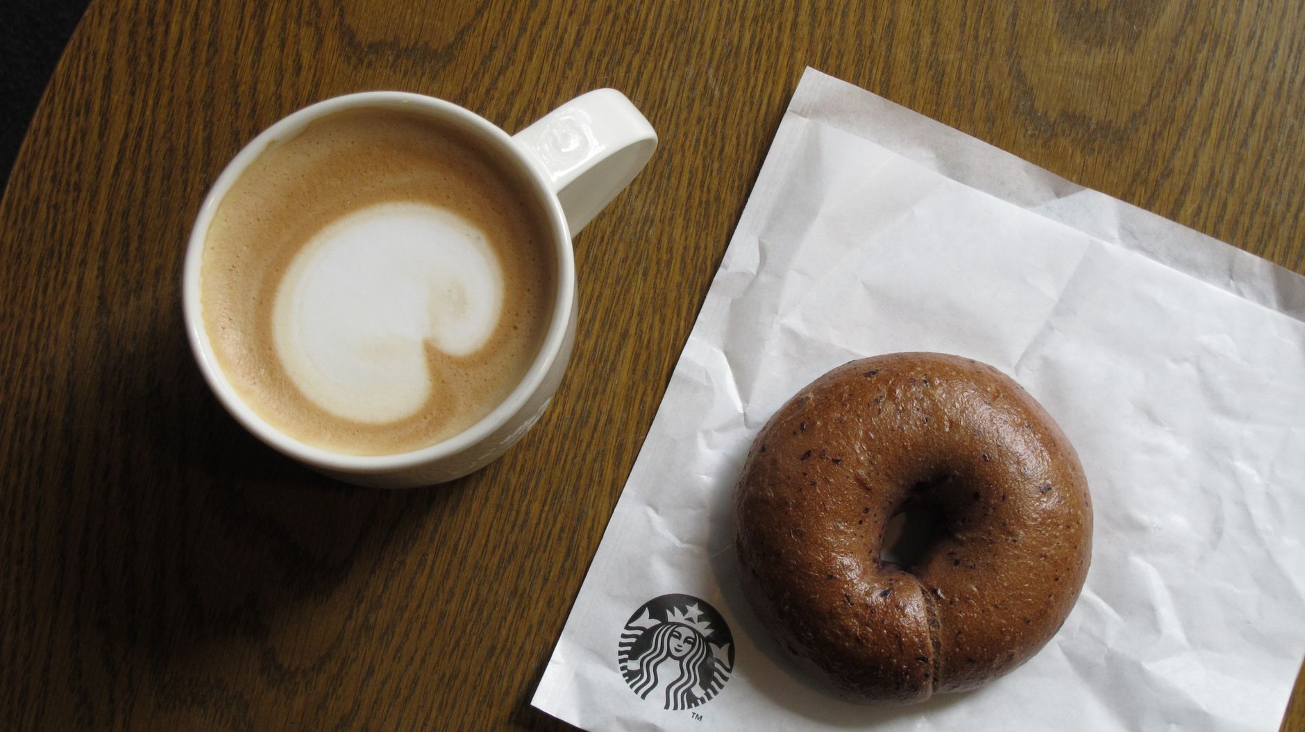 Kaffee mit Latte Art und Bagel auf einem Holztisch